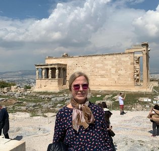 Die blonde Reiseleiterin Janina Flederyte-Vaitiekaitiene steht mit Sonnenbrille vor alten Ruinen.