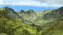 Von einem Gipfel hat man entlang grüner Berge einen weiten Blick ins Tal.