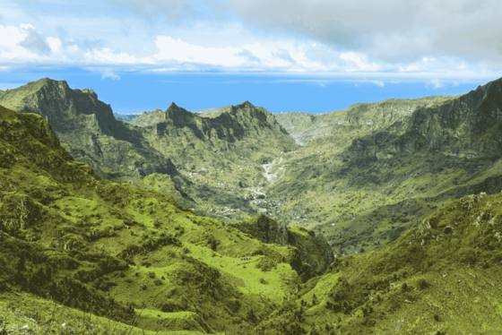 Von einem Gipfel hat man entlang grüner Berge einen weiten Blick ins Tal.