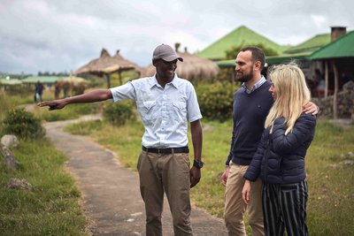 Ein Touristenpaar besucht mit einem privaten Reiseführer das Africa Amini Alama-Projekt in Tansania.