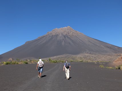 Zwei Wanderer von hinten auf dem Weg zum Vulkan Pico de Fogo durch graue Vulkanlandschaft.