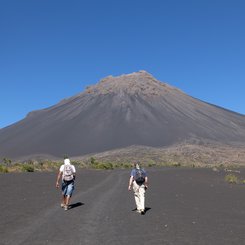 Zwei Wanderer von hinten auf dem Weg zum Vulkan Pico de Fogo durch graue Vulkanlandschaft.