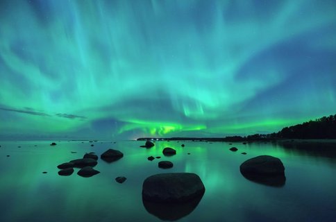 Tanzende Nordlichter am Himmel über einer weiten Fjordlandschaft