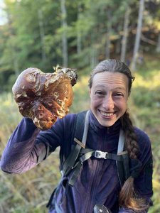 Ein Bild von der Reiseleiterin Oana Hristov, die im Wald strahlend einen großen Pilz ins Bild hält.