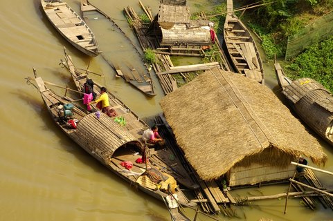 Eine Familie geht auf Booten an einem schwimmenden Haus ihrer Arbeit nach