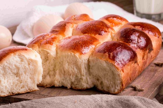 Traditionelle Milchbrötchen aus São Tomé, auch bekannt als Pão Doce, serviert auf einem Teller. Die Brötchen sind goldbraun gebacken und haben eine weiche, flaumige Textur. Ideal als süßes Frühstück oder Snack.