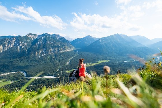 Eine Frau genießt nach dem Wandern die Aussicht auf die Alpen.