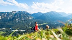 Eine Frau genießt nach dem Wandern die Aussicht auf die Alpen.