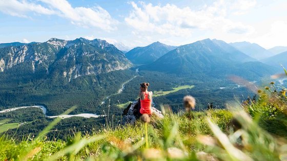 Eine Frau genießt nach dem Wandern die Aussicht auf die Alpen.