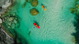 Obersicht auf zwei Kajakfahrer über einen smaragdgrünen Fluss 