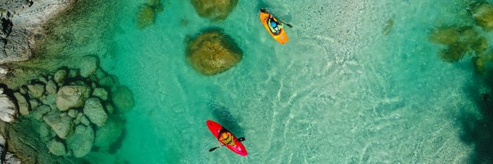Obersicht auf zwei Kajakfahrer über einen smaragdgrünen Fluss 