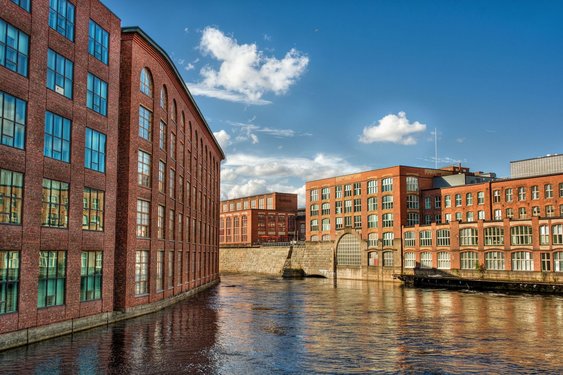Entlang eines Flusses zeihen sich historische Fabrikgebäude.