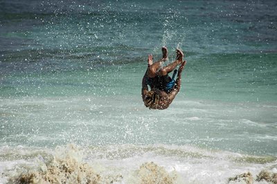 Junger Mann macht einen Salto im Meer.