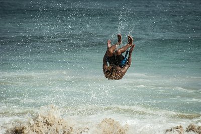 Junger Mann macht einen Salto im Meer.