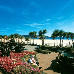 Menschen sitzen auf einem mit Blumen schön angelegten Platz auf einer Strandpromenade auf Jersey