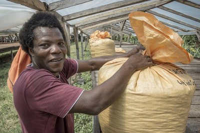 Ein Kakaobauer mit einem Sack voll Kakaobohnen