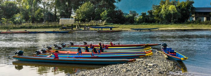 bunte, lange, schmale Boote liegen am Ufer