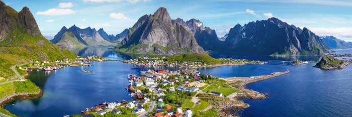 Dorf umgeben von Wasser und im Hintergrund spitze berge