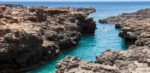 Touristen schwimmen entlang einer steinigen Bucht 