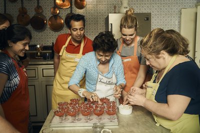 Gruppe schaut zu wie Köchin das Dessert zubereitet