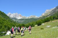 Eine Gruppe wandert über eine ansteigende Wiese in den Albanischen Alpen.