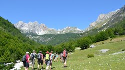 Eine Gruppe wandert über eine ansteigende Wiese in den Albanischen Alpen.