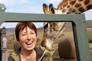 Eine EcoVolunteer-Teilnehmerin wird von einer Giraffe begutachtet.