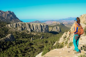 Frau wandert durch das Aitana Gebirge und schaut auf die Berge und das Meer im Hintergrund