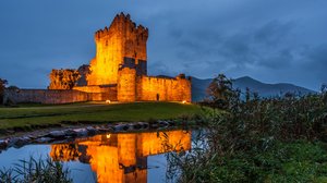 Eine beleuchtete Burg am Abend in Irland an einem Fluss