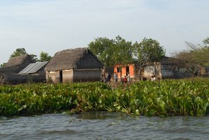 Kleine Hütten und Kinder am Rande eines Flusses
