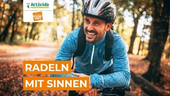 Mann fährt lächelnd auf seinem Fahrrad durch den Wald