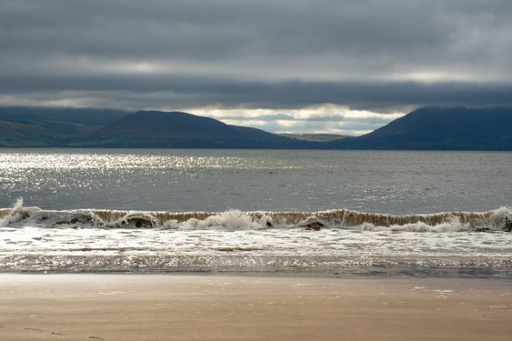 Ein Strand mit Bergen im Hintergrund und grauem Himmel in Minard Castle