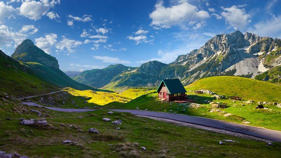 Traumhafte Aussicht auf die Durmitor Berge in Montenegro Blick auf ein Tal mit Hütte vor den Durmitor Bergen unter klarem, blauen Himmel in Montenegro.