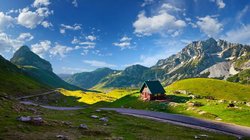 Blick auf ein Tal mit Hütte vor den Durmitor Bergen unter klarem, blauen Himmel in Montenegro.