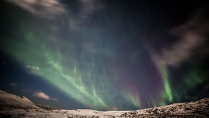 DAs faszinierende Schauspiel Aurora Borealis Über einem Streifen schneeiger Landschaft leuchtet der Himmel mit grünen Polarlichtern.