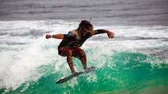 Ein Surfer reitet auf einer türkisen Welle.