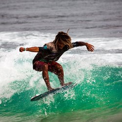 Ein Surfer reitet auf einer türkisen Welle.