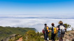 Eine Wandergruppe blickt vom Gipfel aus über die Landschaft