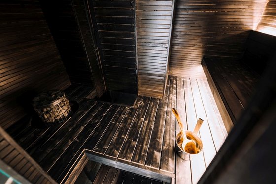 Sauna in der Haltia Lake Lodge Man blickt in das Innere einer Sauna, die mit dunklem Holz ausgestattet ist.