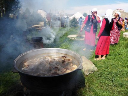 Frauen kochen auf einer Wiese einen Eintopf