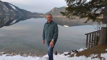 Reisen mit Sinnen-Reiseleiter Zbigniew Sentycz, der vor einem See und verschneiten Bergen steht.