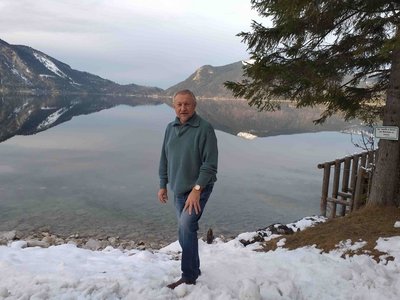 Reisen mit Sinnen-Reiseleiter Zbigniew Sentycz, der vor einem See und verschneiten Bergen steht.