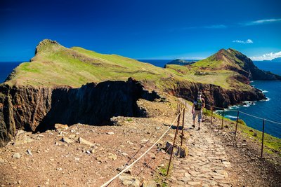 Wanderer läuft auf einem Weg entland einer Felszunge am Meer