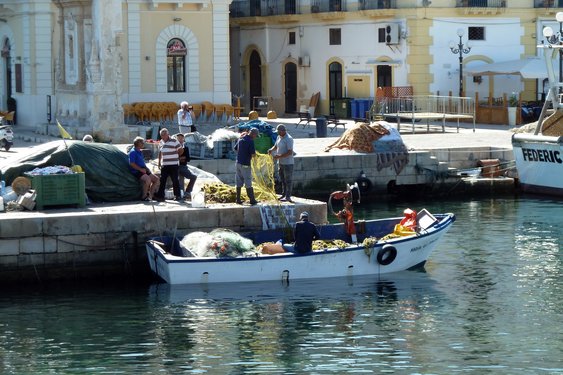 Apulien Weinreise in Italien Fischer beladen ein kleines Boot im Stadthafen