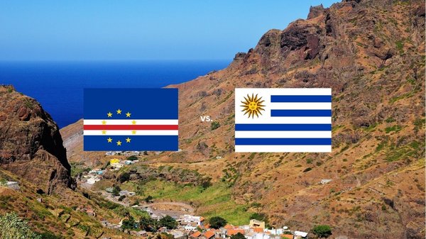 Auf dem Bild sind die Flaggen der Kapverden und von Uruguay abgebildet. Im Hintergrund ist eine bergige Landschaft der Kapverden direkt am Meer abgebildet.