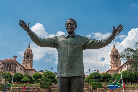 Statue mir erhobenen ausgebreiteten Armen, im Hintergrund sind die Union Buildings zu sehen