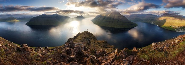 Ein Wanderer blickt über die atemberaubende Landschaft der Färöer-Inseln