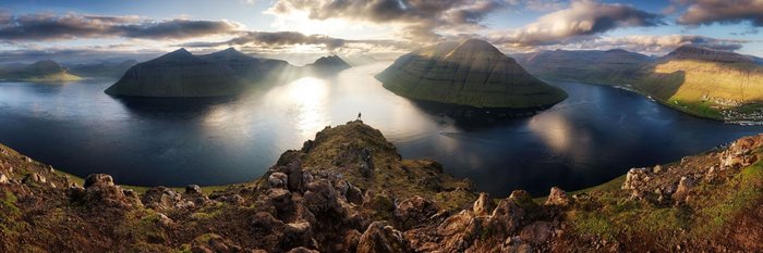 Ein Wanderer blickt über die atemberaubende Landschaft der Färöer-Inseln