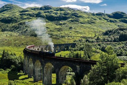 alte Dampflok fährt durch eine Berglandschaft