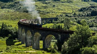alte Dampflok fährt durch eine Berglandschaft